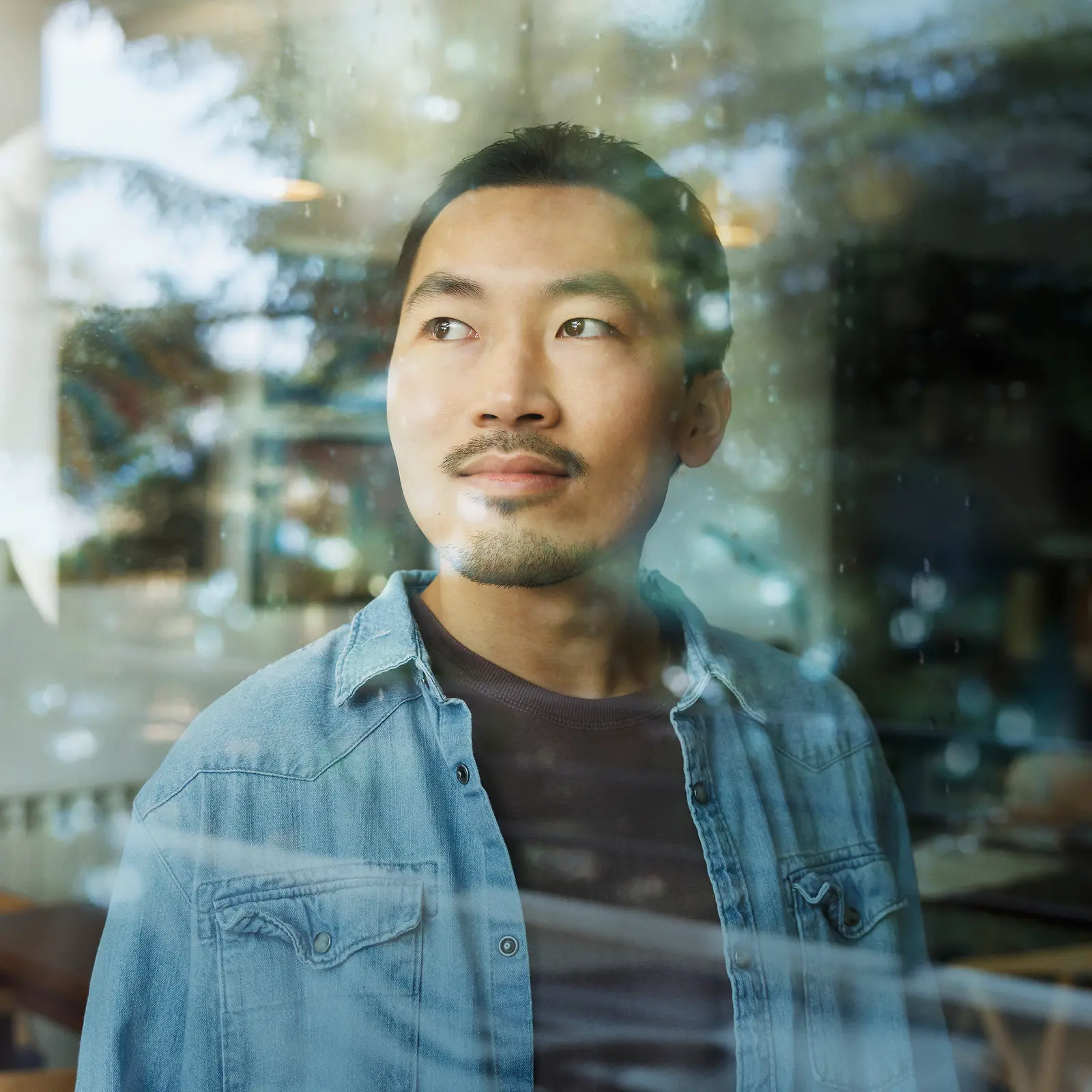 A man looks through a glass window.